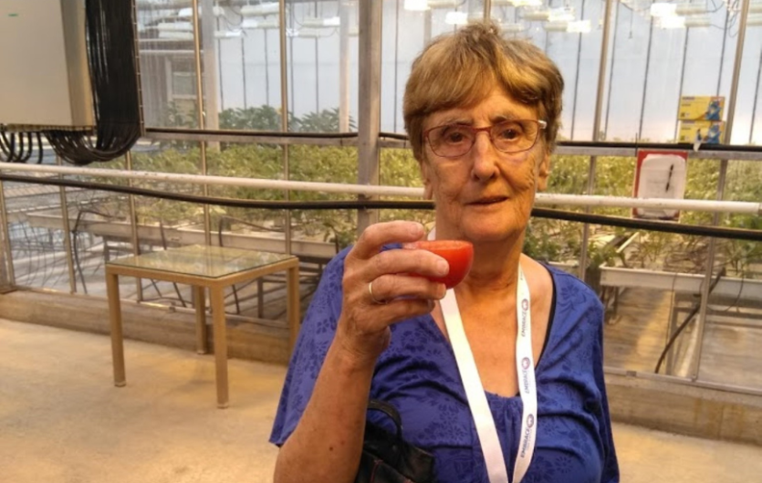 A woman looking at the camera and holding a glass up