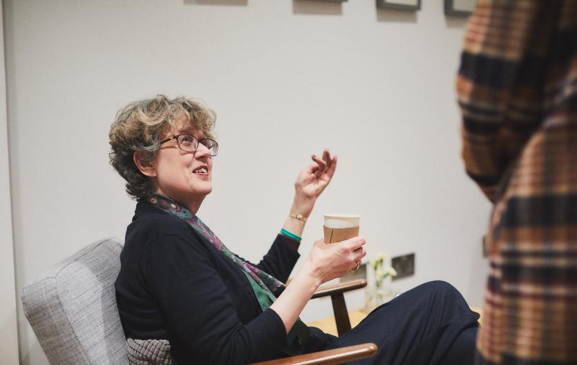 Is stammering a disability? A woman sitting, listening to someone standing next to her