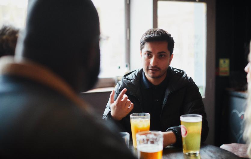 A man talking to a friend in a pub setting