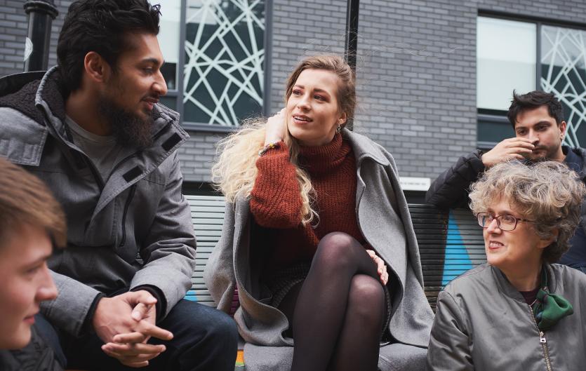 Five people talking, sitting outside in an urban setting
