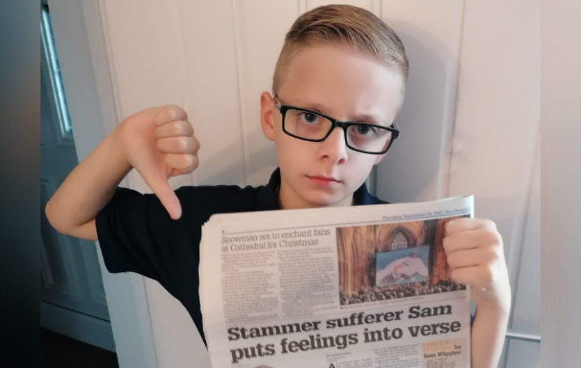 Sam holding up a newspaper and giving it a thumbs down