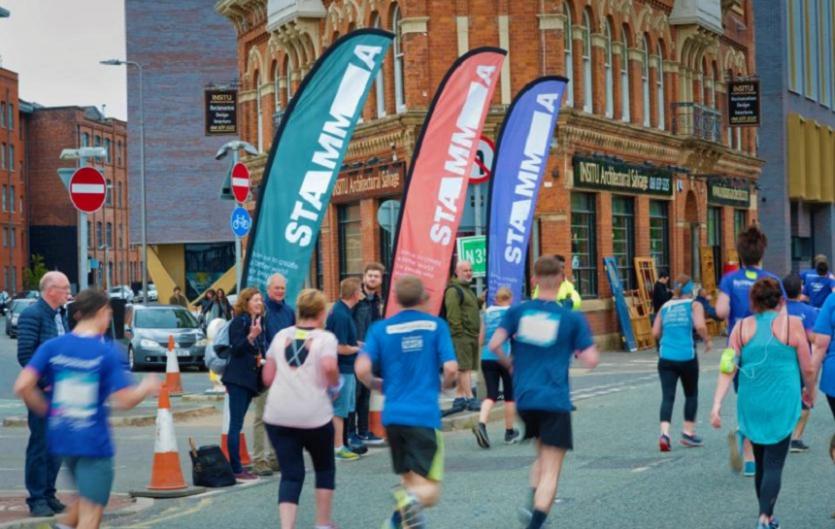 Join STAMMA Street Teams 10k Runners running past STAMMA banners, with supporters cheering them on