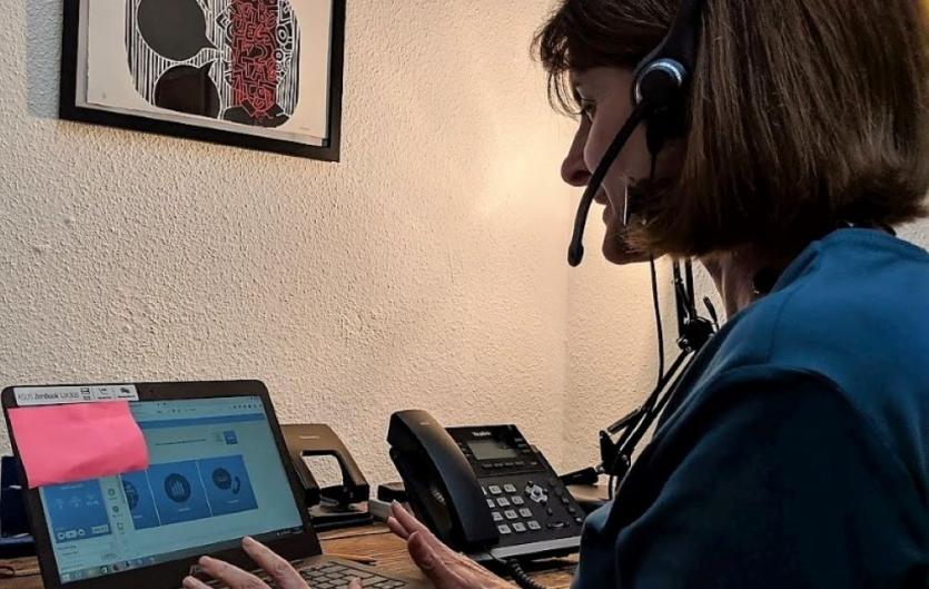 New helpline & webchat opening hours A woman wearing a telephone headset and looking at a laptop computer