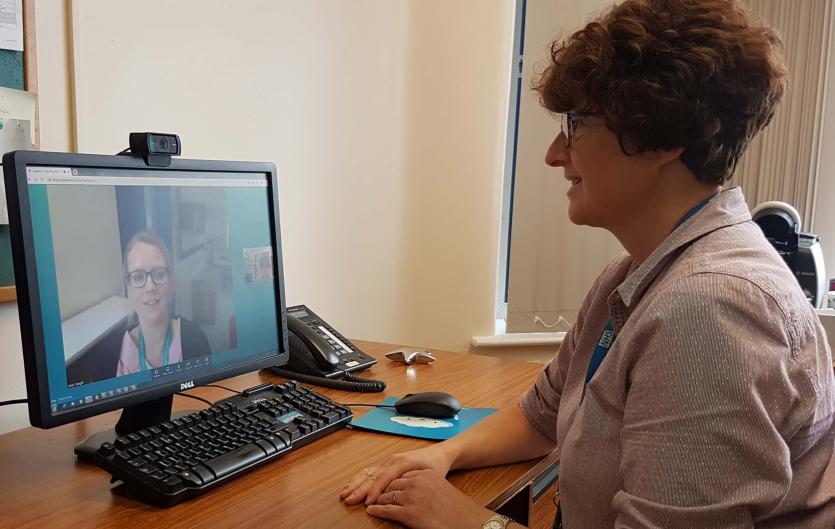 A woman in a therapy setting making a video call on the computer