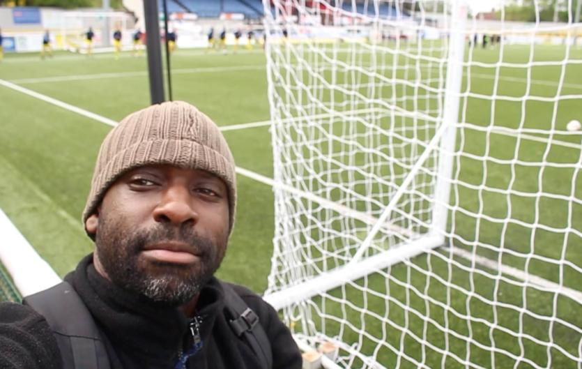 Sorry, can you repeat that? A man in front of football goal posts looking at the camera