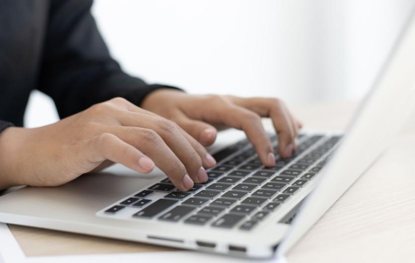 A close up on a person's hands typing on a laptop computer