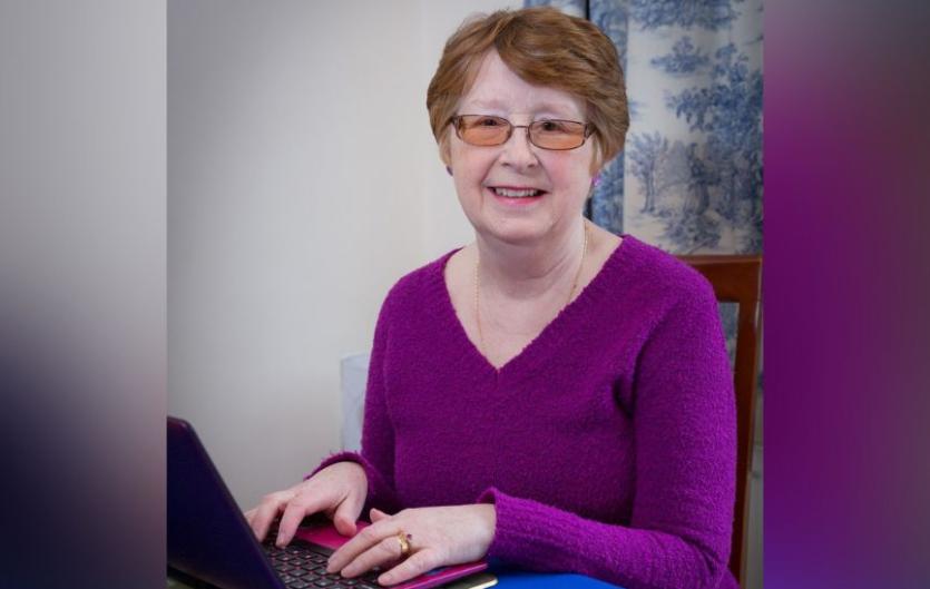 A woman typing on a laptop computer and looking at the camera