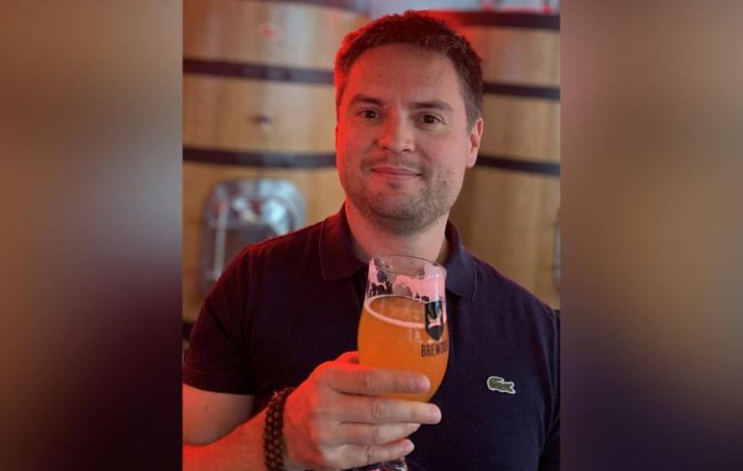 Don't see stammering as holding you back A man holding a drink and looking at the camera, smilling