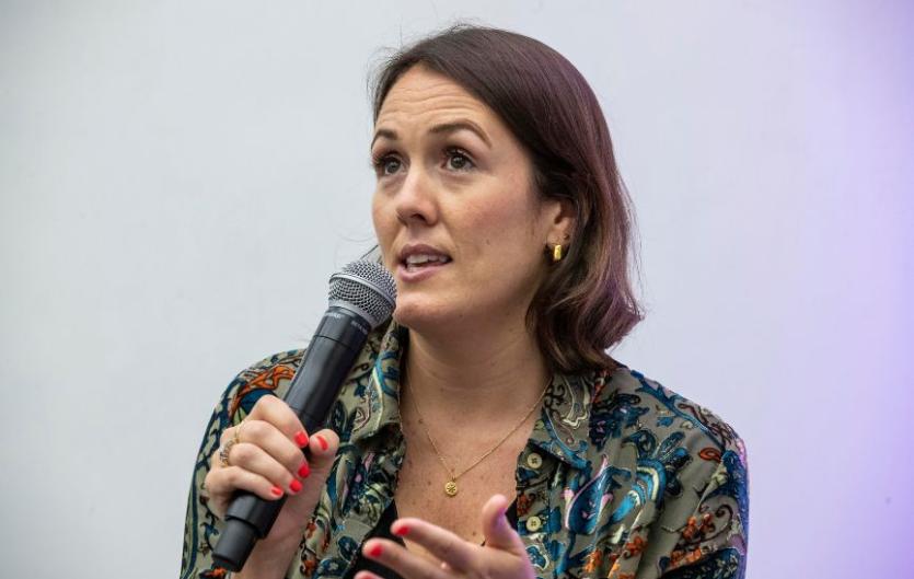 A woman speaking into a microphone and looking to the left