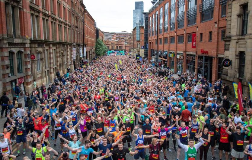 Fundraise A crowd of people doing a sponsored run, looking at the camera