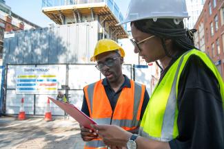 A man and a woman in construction wear looking at a clipboard