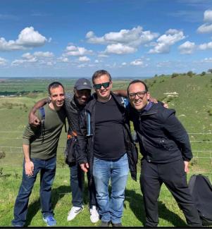 Four men in an outdoor setting linking arms