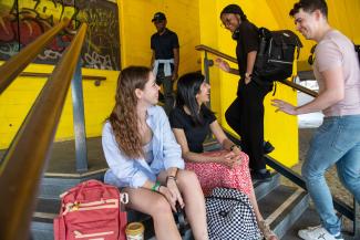 Two women sitting on steps looking at a man and a woman who are walking up the steps