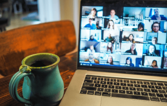 A laptop computer displaying a video call in process with a mug beside it