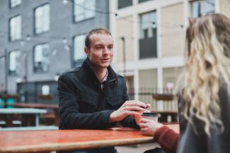 A man sitting on a bench in conversation with a woman whose back is turned to the camera