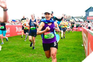 A woman running in a charity event, wearing a flag as a cape