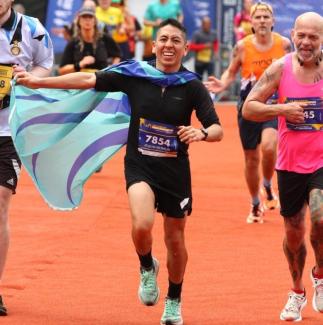 A man running in a charity event wearing a flag as a cape