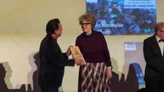 A man presenting a woman with an award on stage