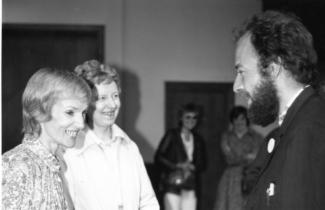 Two women on the left speaking to a man on the right