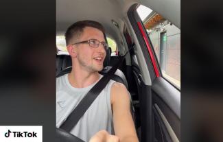 A man behind the steering wheel of a car looking out of the window