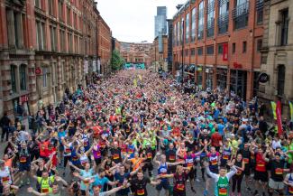 A street full of charity runners all looking at the camera waving their hands