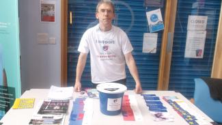 A man standing behind an information desk, looking at the camera