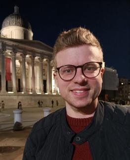 A man smiling for the camera with London's Gallery behind him