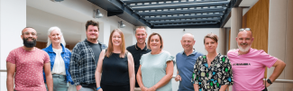 Five men and four women standing together and smiling