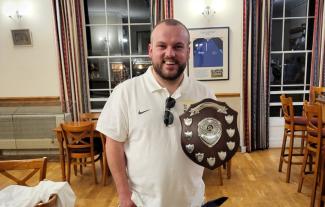 A man holding a trophy, smiling for the camera