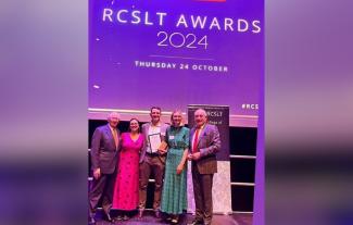 A group of people standing on a stage, a man in the group holding an award