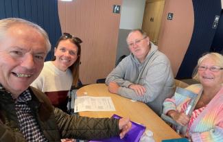 Four people sitting around a table and smiling