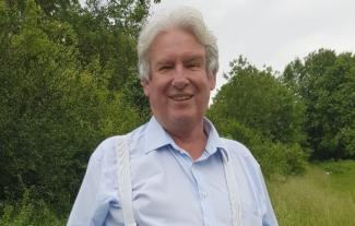 A man in an outdoor setting, smiling