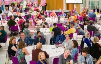 Tables in a large room, with people sitting at them and chatting