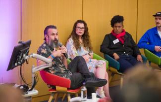 A panel of people, with one man speaking into a microphone