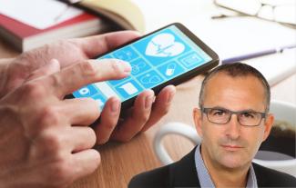 A man's face, in front of a hand using a smartphone