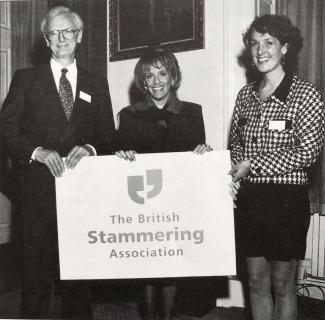 A man and two women holding a banner with 'British Stammering Association' on it
