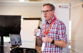 A man wearing a lanyard standing and doing a presentation