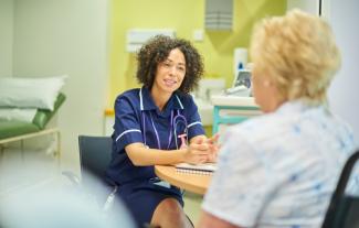 A female nurse at a desk talking with a patient