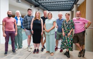 Five men and four women standing together and smiling