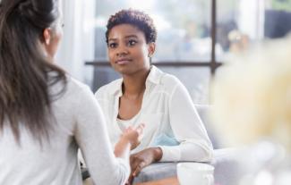 A woman in a therapy setting, talking to another woman, whose face we cannot see
