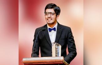 A man in a suit speaking at a lecturn