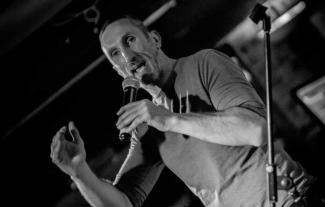 A man holding a microphone, doing stand up comedy