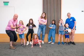 A group of children smiling, with two grown ups