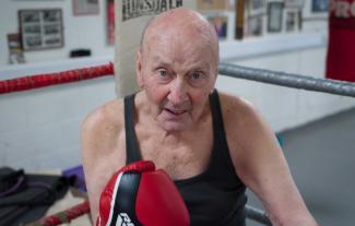 A man wearing boxing gloves smiling