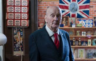A man in a suit standing in a museum looking at the camera