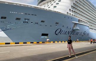 A woman standing in front on a cruise ship and smiling