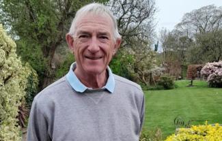 A man standing in a garden and smiling