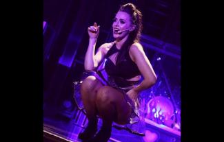 A woman singing on stage, in a crouched position