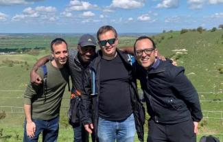 Four men standing together and smiling in the coountryside
