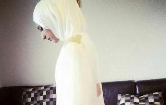A woman in islamic clothint looking to the floor, from a side view